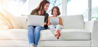 Mother on laptop and daughter on tablet