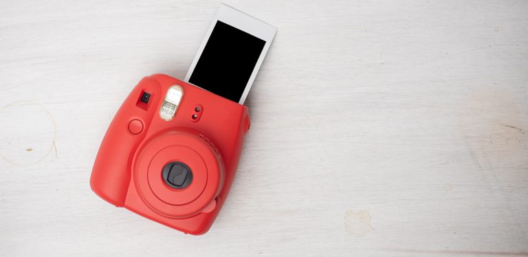 Red instant camera spitting out undeveloped photo