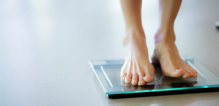 Woman standing in bare feet on a bathroom scale