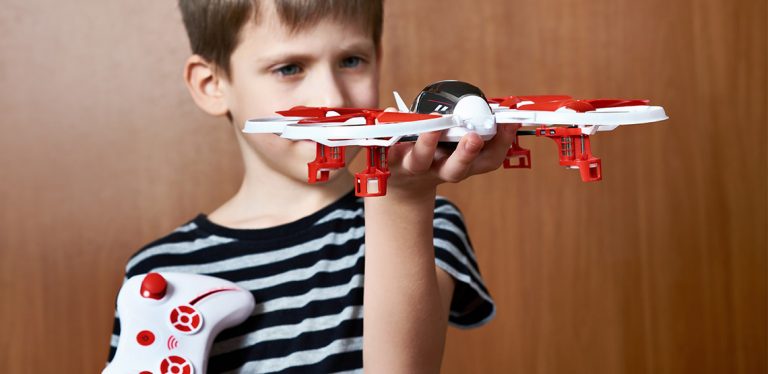 Boy holding a drone in one hand and a controller in the other