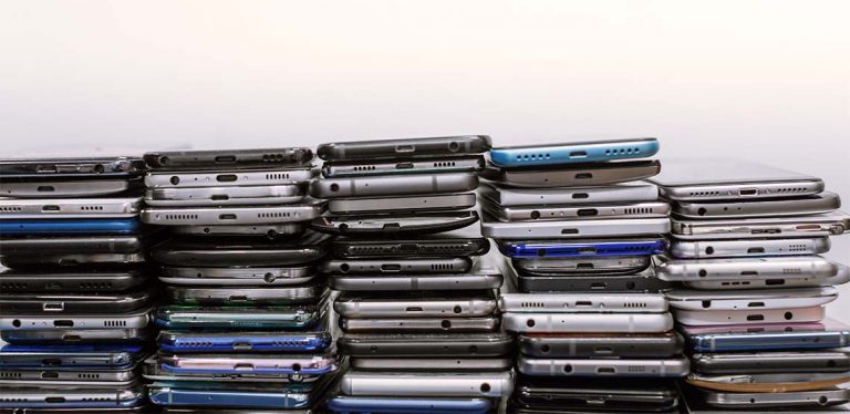 A stack of different brands of phones lined against a white background.